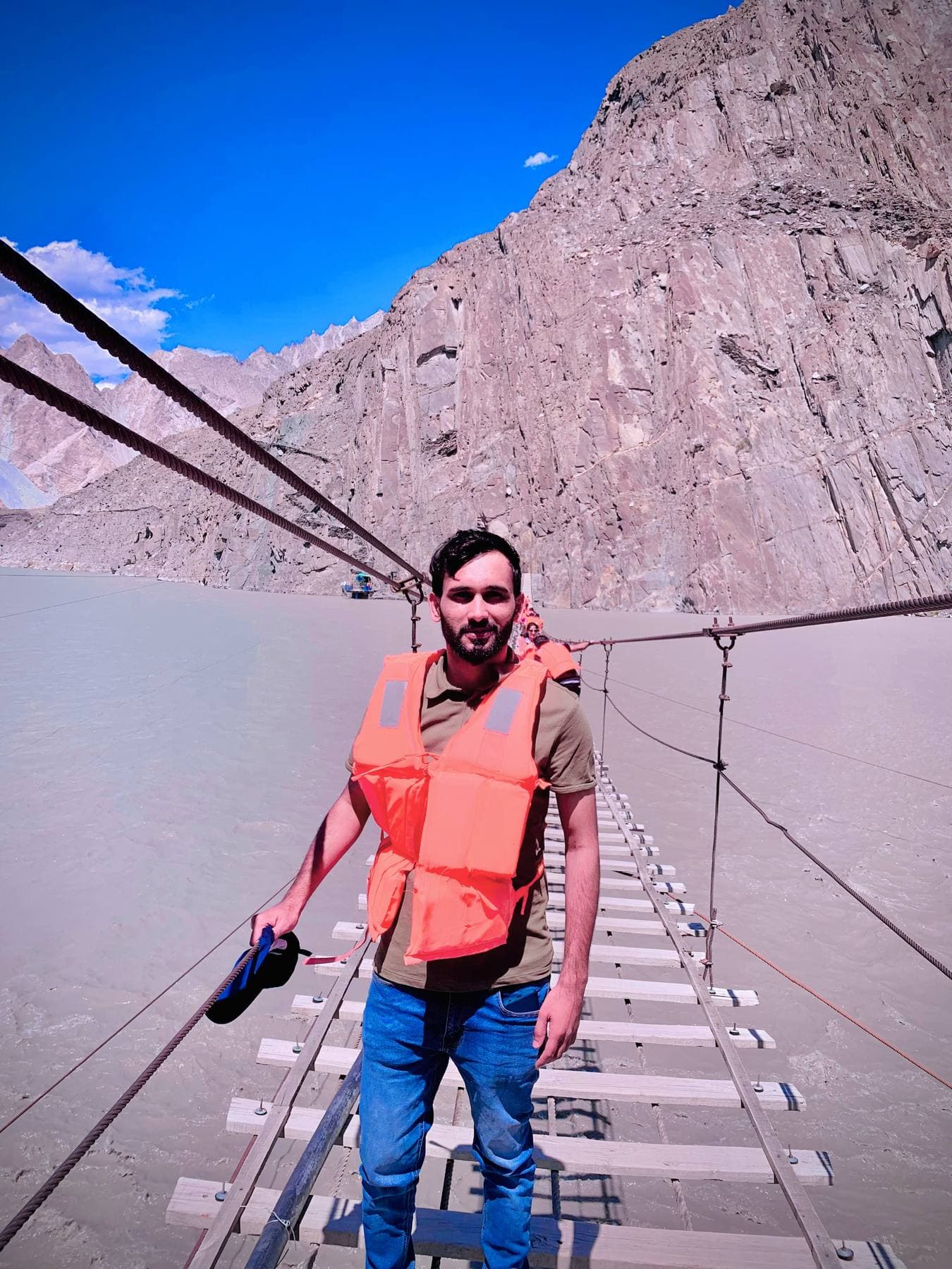 Life vest on, crossing a swaying suspension bridge over the glacial river.