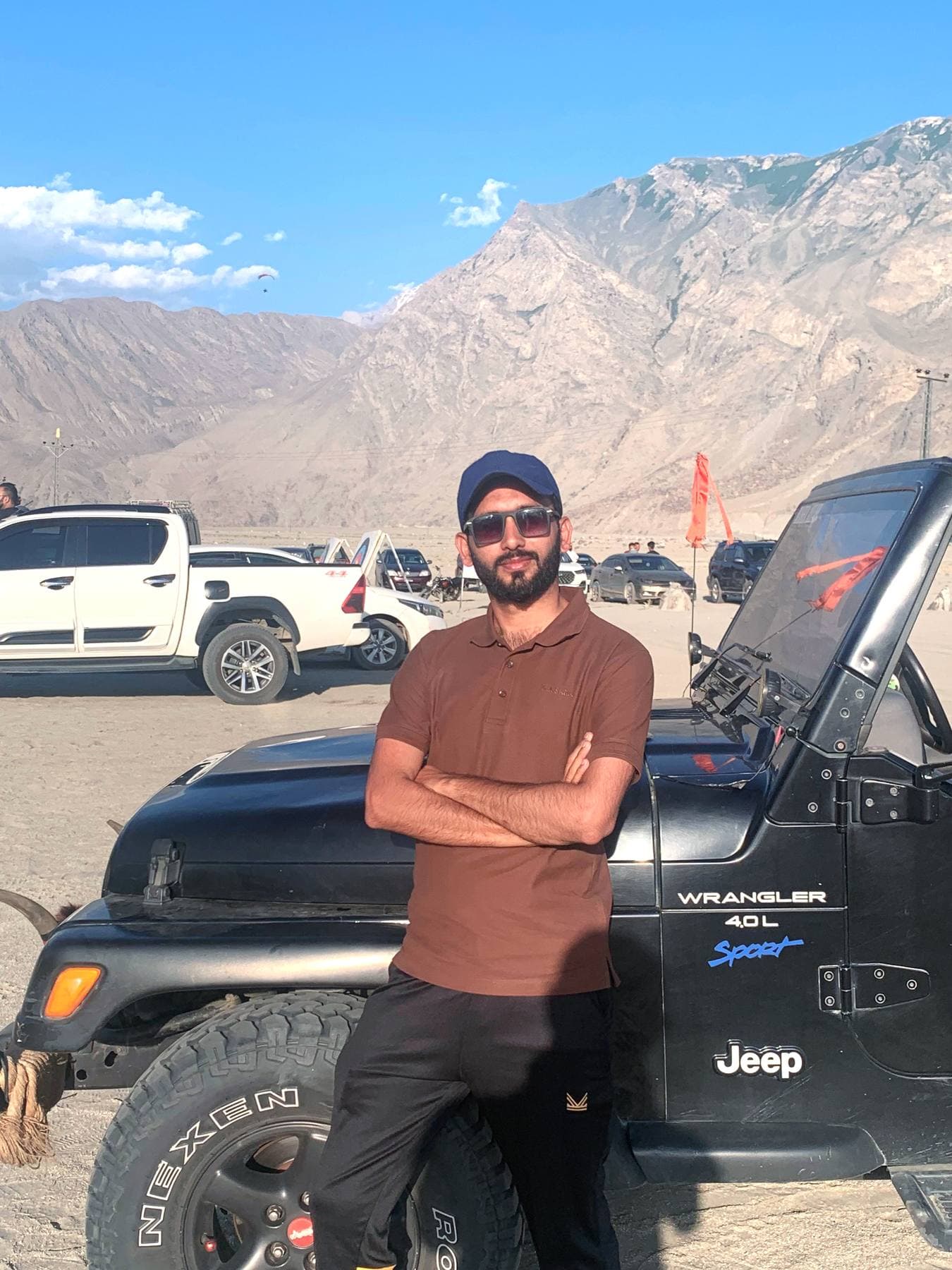 Cold desert flats outside Skardu — jeeps, dust, and paragliders overhead.